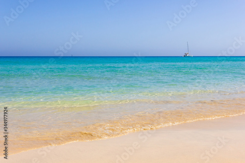 Sailing boat far away on turquoise water empty beach in Fuerteventura. Idyllic natural landscape view from seashore. Summer travel, secluded in paradise concepts © Josu Ozkaritz