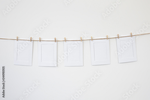 marcos de fotos blancos de papel colgados con pinzas de madera photo
