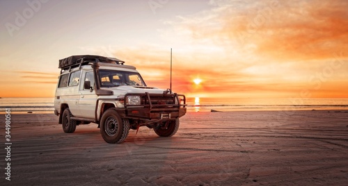 Outback relaxing adventure with 4WD vehicle at the beach of an ocean at sunrise 