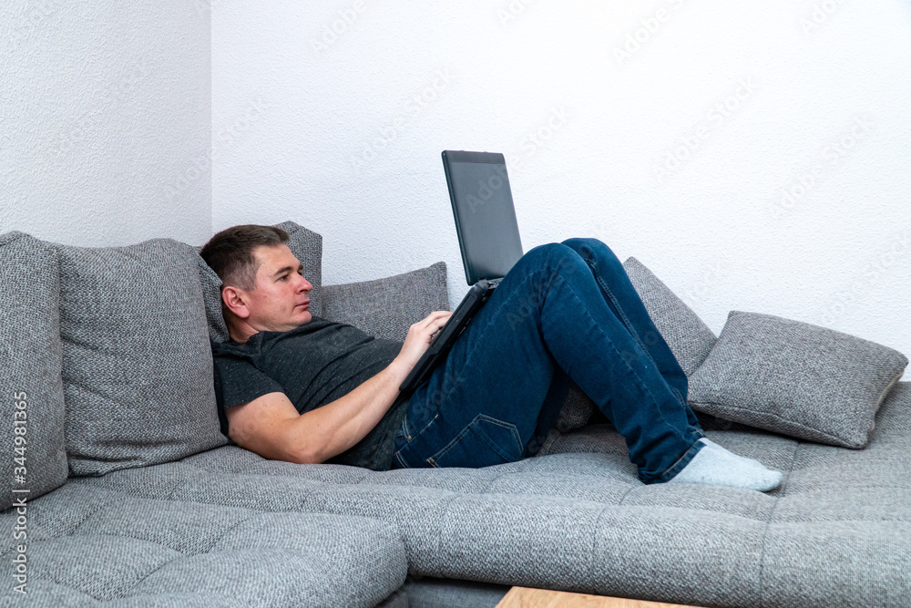 Businessman is tired and lays on a sofa to work on the laptop.