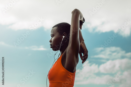 African woman with earphones doing stretching exercise photo