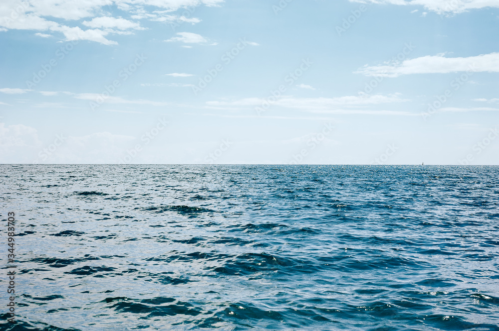 Blue sea with waves and blue cloudy sky