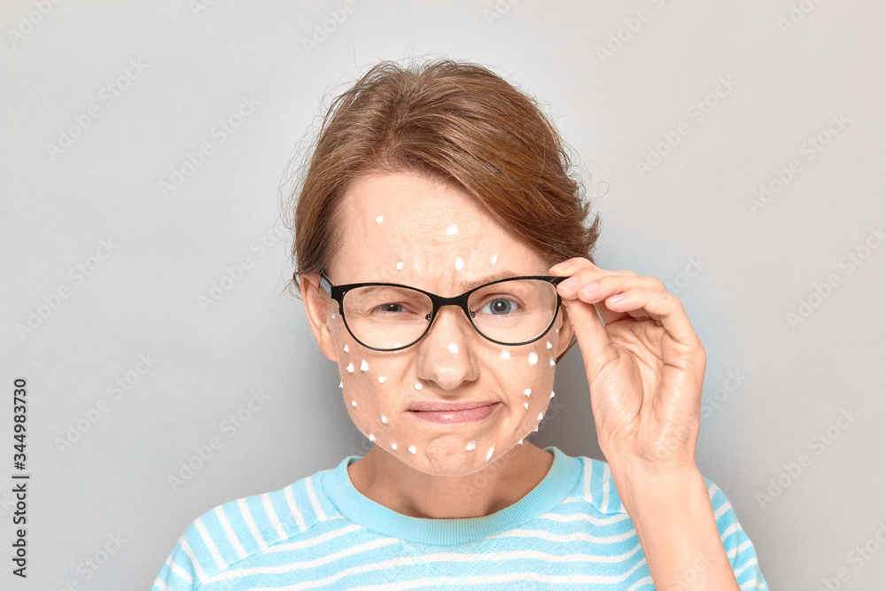 Portrait of annoyed girl with white drops of face cream on skin
