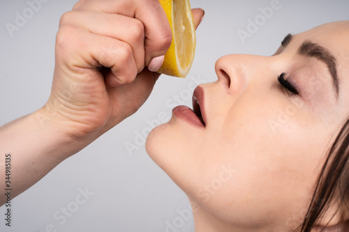 Wallpaper Mural Girl holds in his hand the half of a lemon, it compresses it to squeeze the juice to taste, a little open mouth, face in profile Torontodigital.ca