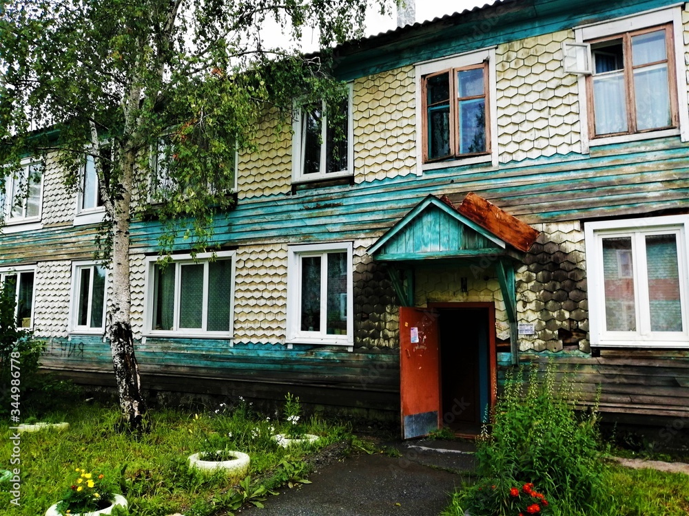 Two-story wooden house in a rainy weater with an open door.Russia.
