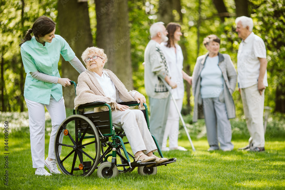 Group of senior patients with caregiver in the garden of nursing home Group of senior patients with caregiver in the garden of nursing home