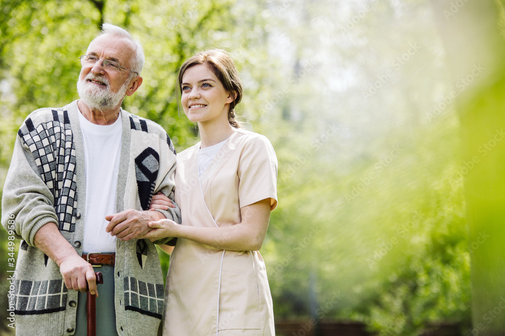 Naklejka premium Senior man with helpful volunteer in the garden of professional care home