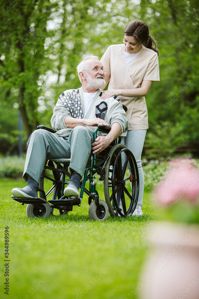 Senior man on the wheelchair in the garden of professional nursing home Senior man on the wheelchair in the garden of professional nursing home