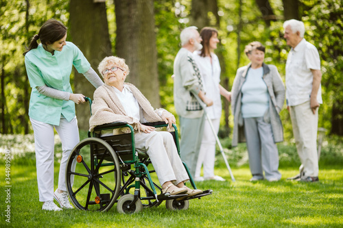Group of senior patients with caregiver in the garden of nursing home