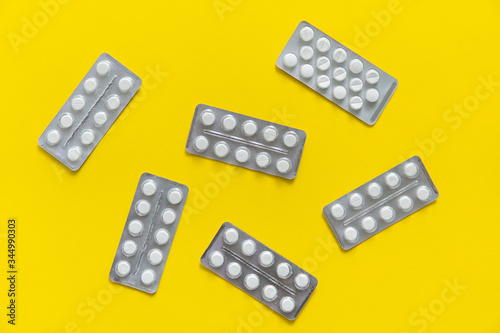 Top view on the pills in the package. White pills on yellow background. Medicine, medication, painkillers, tablet, medicaments, drugs, antibiotic, vitamin, treatment, capsule, dose. Pharmacy theme.