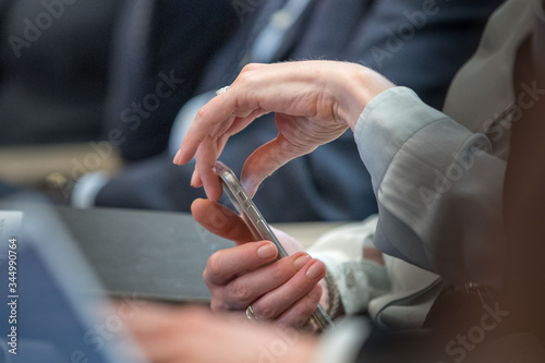Closeup of hands scrolling smartphone while in meeting
