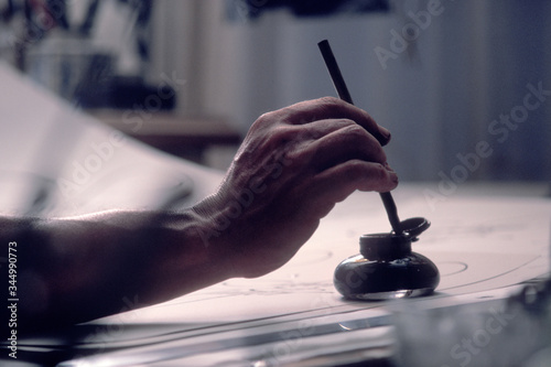 Photography Hand of calligrapher dipping pen into inkwell