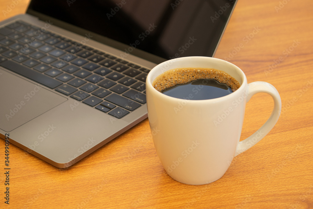 White cup of coffee next to a laptop White cup of coffee next to a laptop