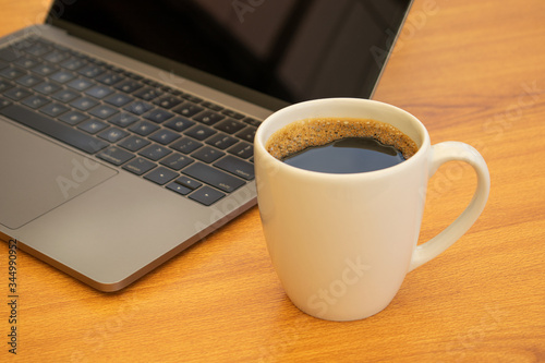 White cup of coffee next to a laptop