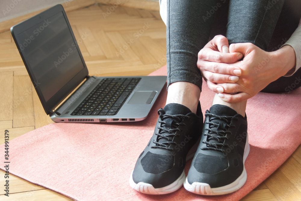 Shot of a yound woman at home, ready for follow your online class of yoga. Sneakers close up. Laptop. Home workout concept