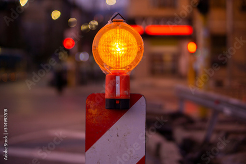 Road construction sign light in orange on a red and white stand