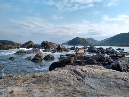 Lindas pedras beira mar com nuvens e céu azul ao fundo