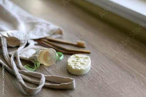 Canvas tote bag with zero waste products: menstrual cup, soap, reusable straws and bamboo toothbrush. Selective focus.