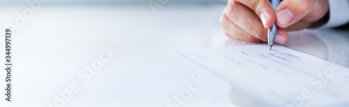 Foto Close-up Of Hand Filling Cheque