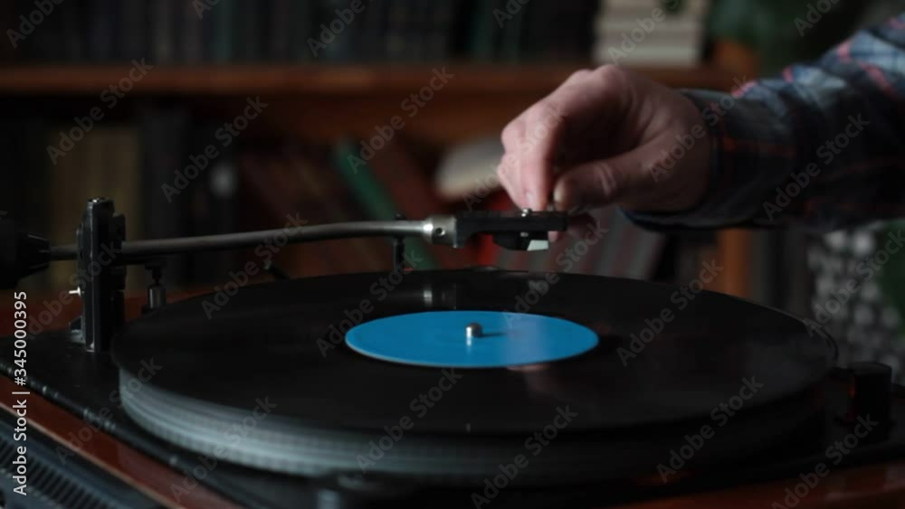Close-up male hand starting retro record player, lay down the needle, selective focus
