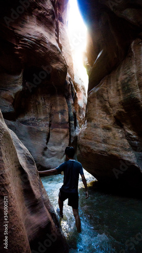 Guy hiking into the canyon through the water to the Kanarraville Falls in Kanarraville, Utah, USA