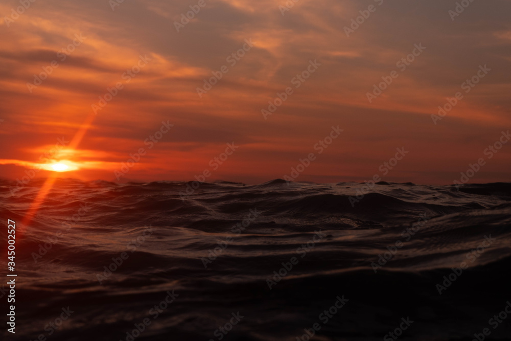 sunset over horizon line in sunset with ripples wave ocean wave low angle view. Close up Nature background.