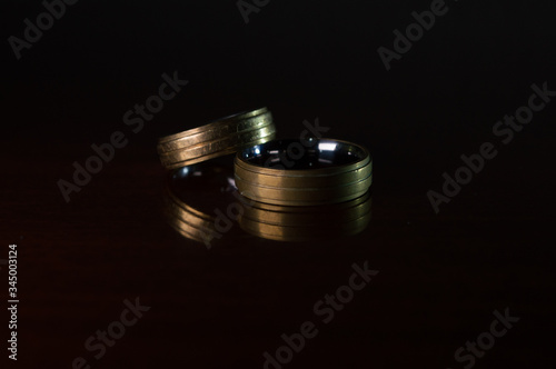 pair of golden wedding rings with silver details, Concept photo with dramatic light, copy space and black background