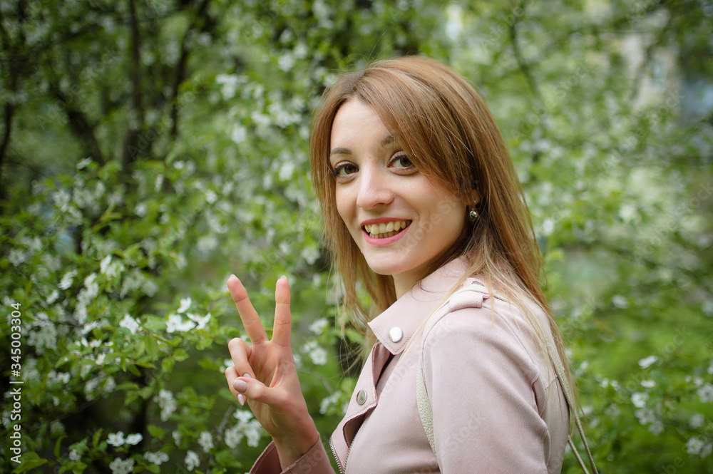 Outdoors portrait of happy smiling woman on flowering tree background in the garden during early spring. Stop allergy concept Outdoors portrait of happy smiling woman on flowering tree background in the garden during early spring. Stop allergy concept