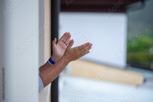 Manos de mujer de mediana edad aplauden desde la ventana en el homenaje diario a los sanitarios. 