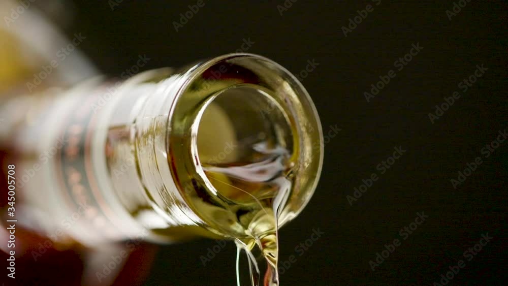 Close up of alcohol pouring out of the mouth of a bottle of alcohol