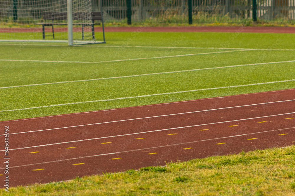 Fototapeta premium Athletics stadium. Outdoor athletics treadmill running track lines with behind football gate.