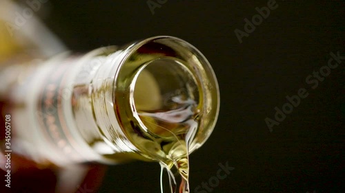Close up of alcohol pouring out of the mouth of a bottle of alcohol