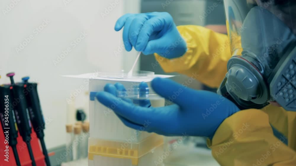Male scientist uses a q-tip while working with coronavirus vaccine in laboratory. Male scientist uses a q-tip while working with coronavirus vaccine in laboratory.