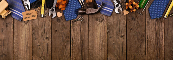 Happy Fathers Day gift tag with top border of gifts, ties and tools on a rustic wood banner background. Above view with copy space.
