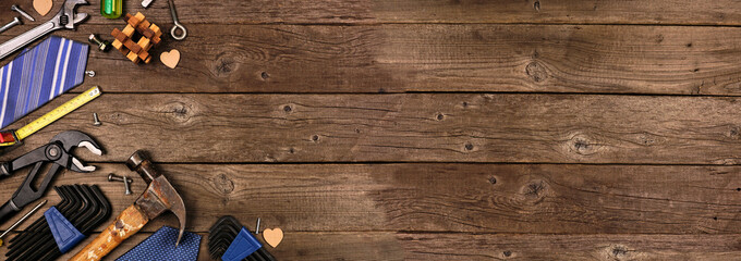 Fathers Day theme corner border of gifts, tie and tools on a rustic wood banner background. Top view with copy space.