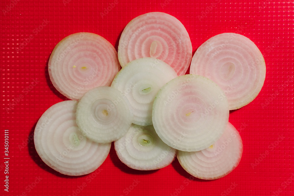 Onion slices on red chopping board Onion slices on red chopping board