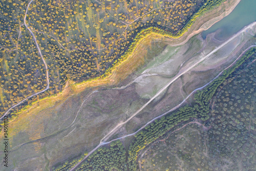 Aerial drone top-down photo of a dried up river in Spain with green lush grassland around it
