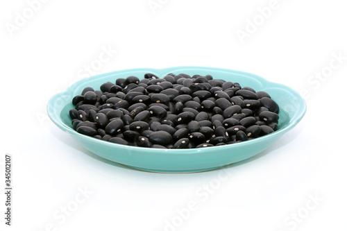 Black turtle bean (Black bean) in dish isolated on white background. In terms of Traditional Chinese Medicine black beans are known for their ability to tonify blood and yin, also regulate water. photo