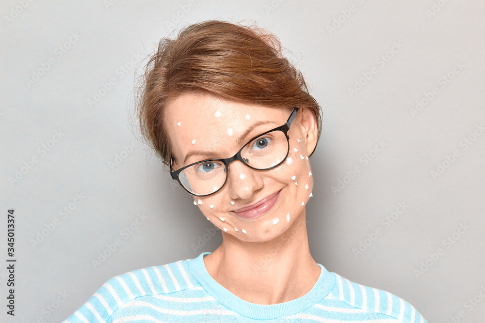 Portrait of happy girl with white drops of face cream on skin Portrait of happy girl with white drops of face cream on skin