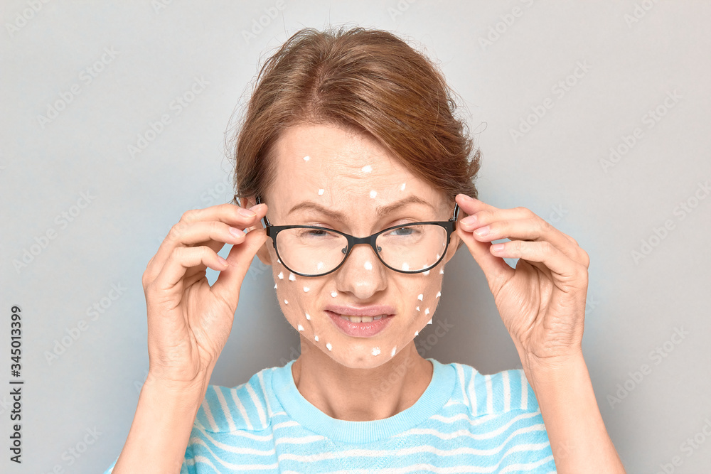 Portrait of annoyed girl with white drops of face cream on skin Portrait of annoyed girl with white drops of face cream on skin