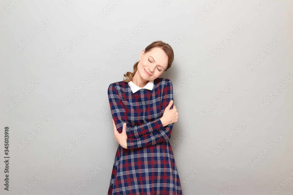 Portrait of cute happy young blond woman embracing herself and smiling Portrait of cute happy young blond woman embracing herself and smiling
