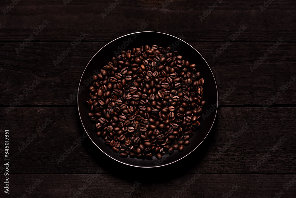 
Coffee beans in a plate on a wooden board.