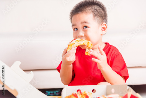 Hot Homemade, Vegetarian fast Italian food, Cute Little Child enjoying eating Delivery Pizza pepperoni, cheese many slices deliciously in an open cardboard box at home