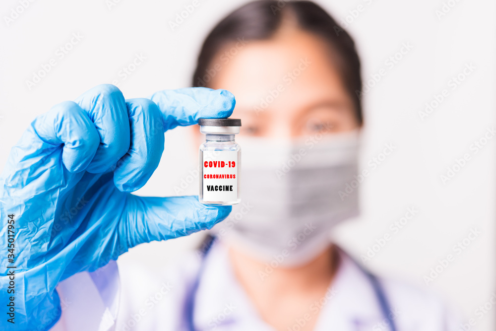 Asian female woman doctor or nurse in uniform and gloves wearing face mask protective in laboratory holding vial corona vaccine bottle on hand and bottle have Asian female woman doctor or nurse in uniform and gloves wearing face mask protective in laboratory holding vial corona vaccine bottle on hand and bottle have