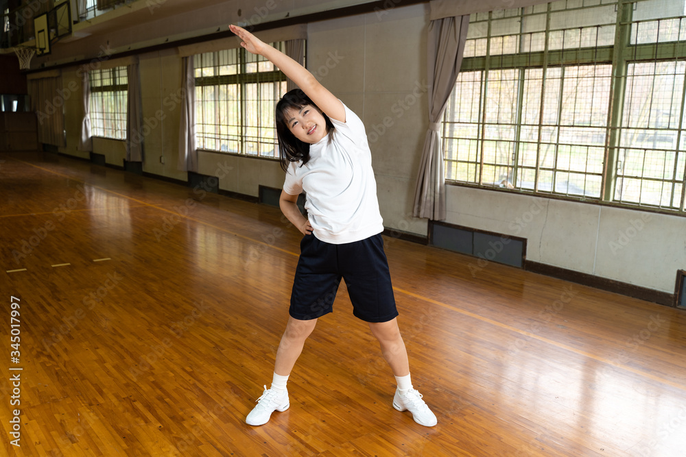 体育館で準備運動をする女子高生 体育館で準備運動をする女子高生