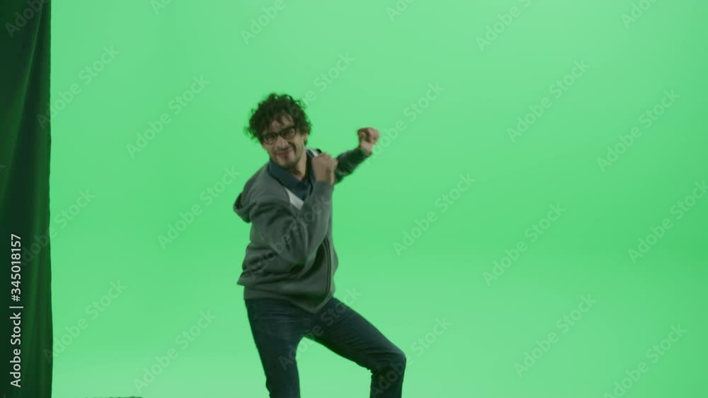 Green Screen Chroma Key Studio: Handsome Smiling Young Man Wearing Casual Clothes Dances. Front View Medium Camera Shot