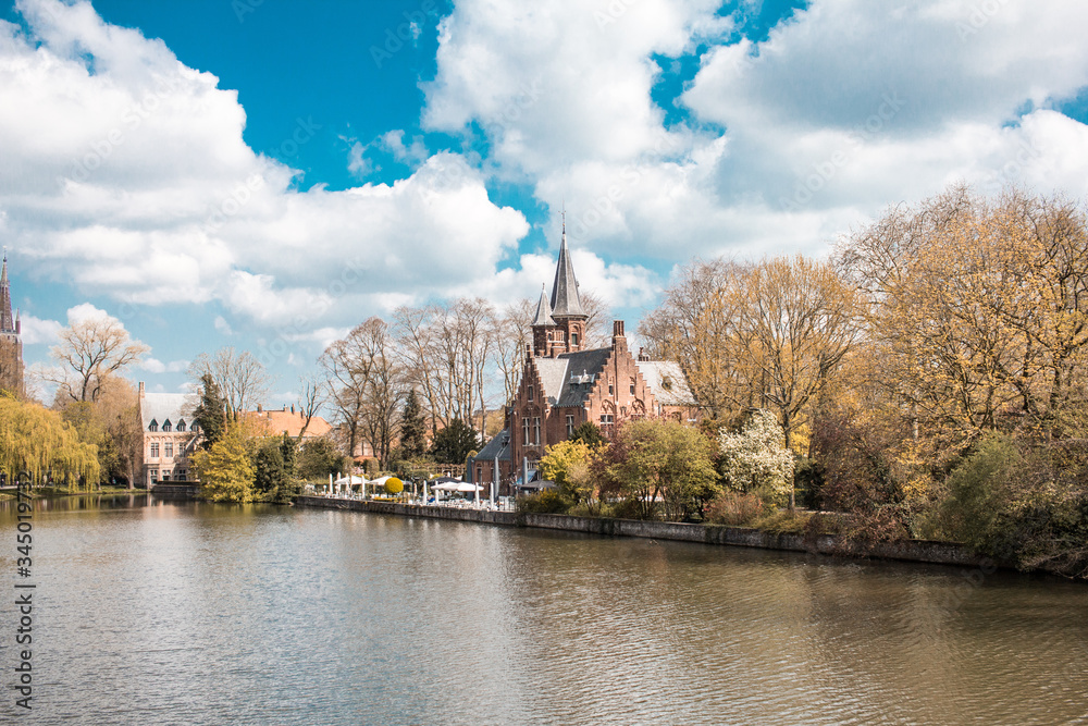 A lake, a sky with many clouds, an old building and a sunny day make for a perfect day in the town of bruges belgium