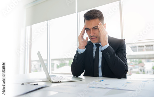 Frustrated stressed businessman feeling tired in black suit having migraine during working at office. Exhausted man having headache and problem about his Financial. Unemployment