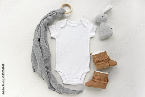 Canvas Print Blank gender neutral white baby bodysuit close up - with toy  and brown booties