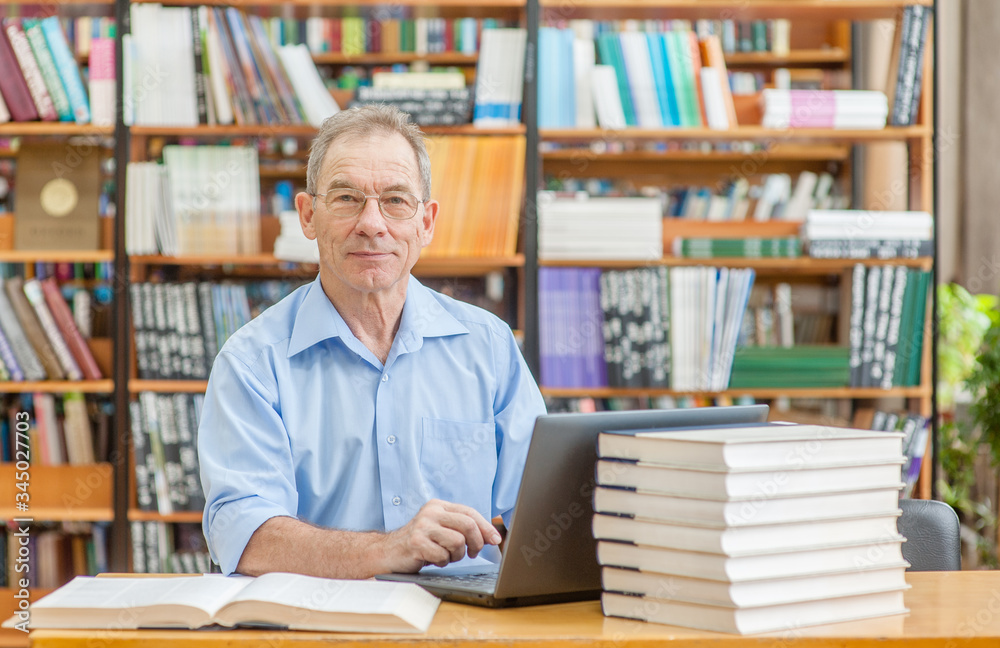 Happy senior man using laptop in library. Empty space for text Happy senior man using laptop in library. Empty space for text